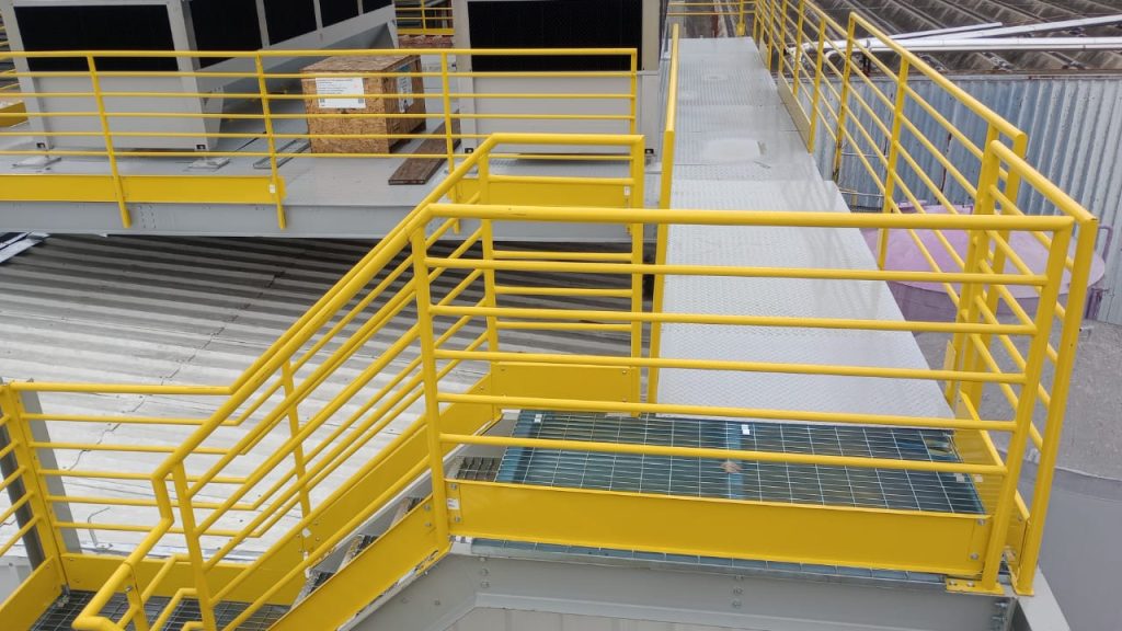 Guarda-corpo metálico amarelo em plataforma e escada de acesso industrial